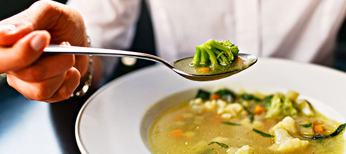 uma mulher segura uma colher de sopa sob o prato