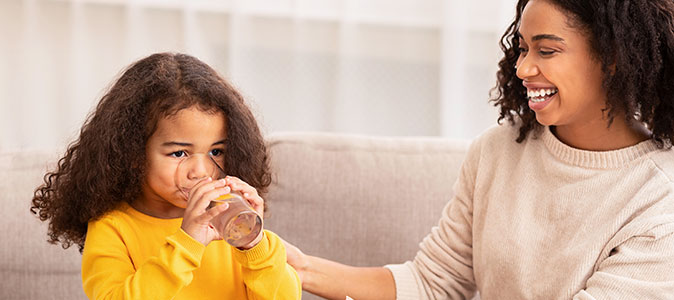 mãe dar um copo de água para sua filha