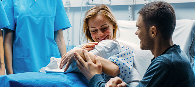 Mulher segura seu bebê numa sala de partos
