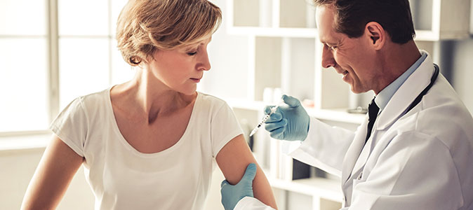 Mulher adulta toma vacina com um médico