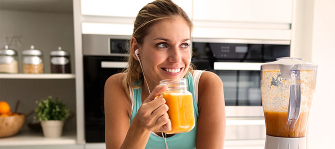 imagem de uma mulher sorrindo com um copo de suco na mão