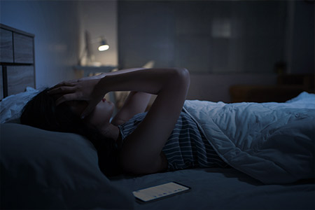 Imagem de uma mulher na cama com falta de sono
