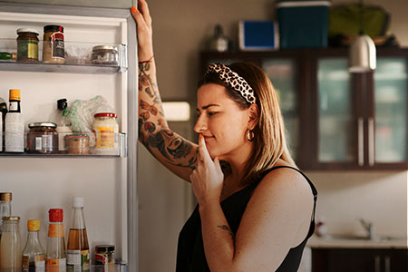 Imagem de uma mulher abrindo a geladeira