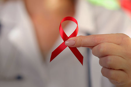 Imagem de uma pessoa segurando a fita em relação a campanha da aids