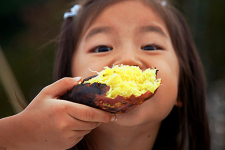 Foto de uma criança comendo batata-doce