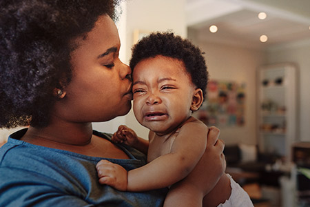 Foto de uma mãe com um bebê chorando no colo