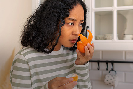 Imagem de mulher testando o olfato em uma casca de laranja
