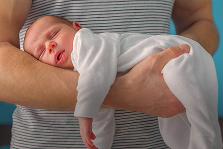 Imagem de um bebê nos braços de um pai