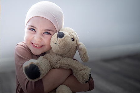 Imagem de uma criança abraçando um boneco de pelúcia