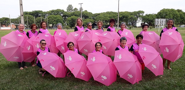 Integrantes do Grupo Amigas do Peito posam para fotos e com seus guarda-chuvas cor de rosas