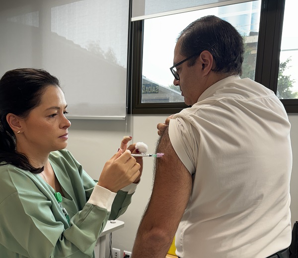 Imagem: Enfermeira aplica vacina em braço de colaborador