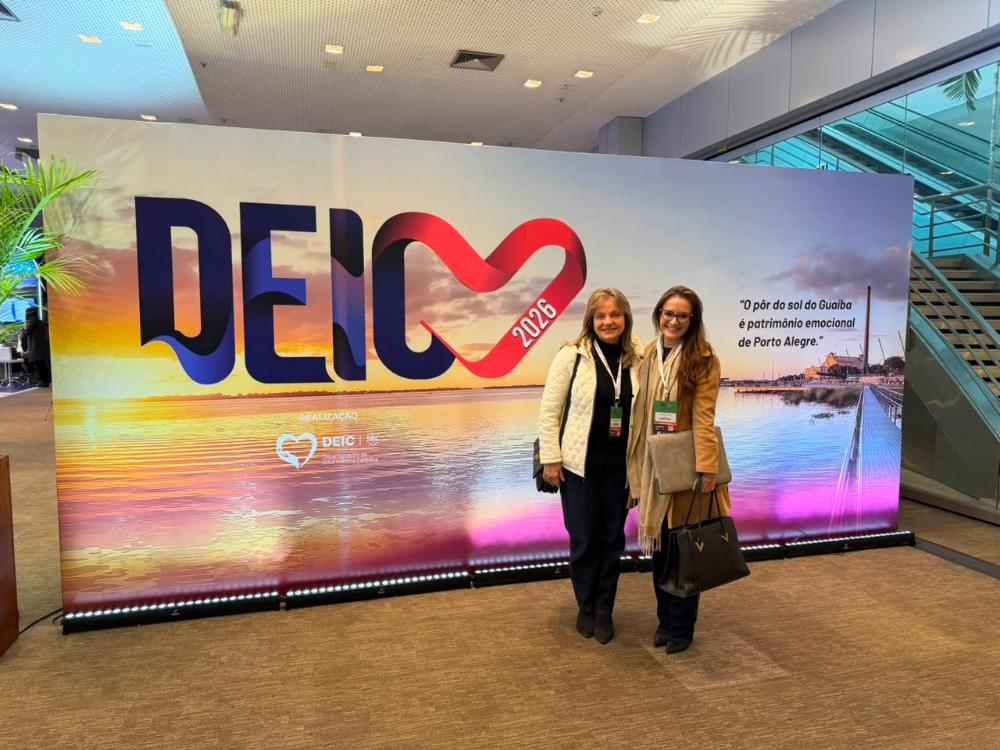 As médicas cardiologistas posam para registro fotográfico diante do painel institucional do congresso DEIC.